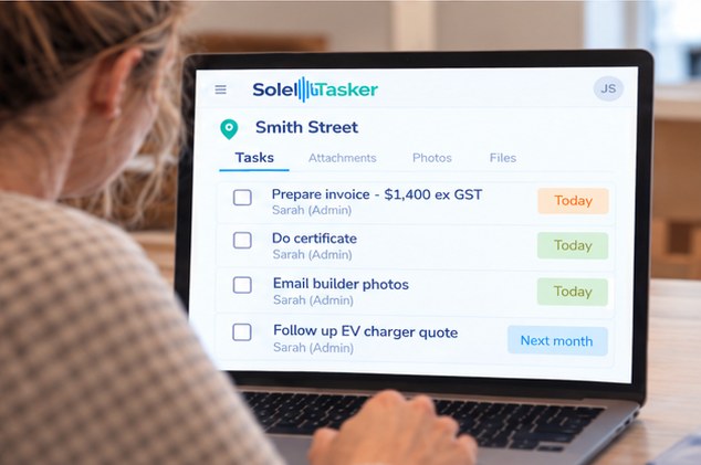 A partner reviews the job’s invoice, certificate and customer photo tasks in SoleTasker on a laptop.